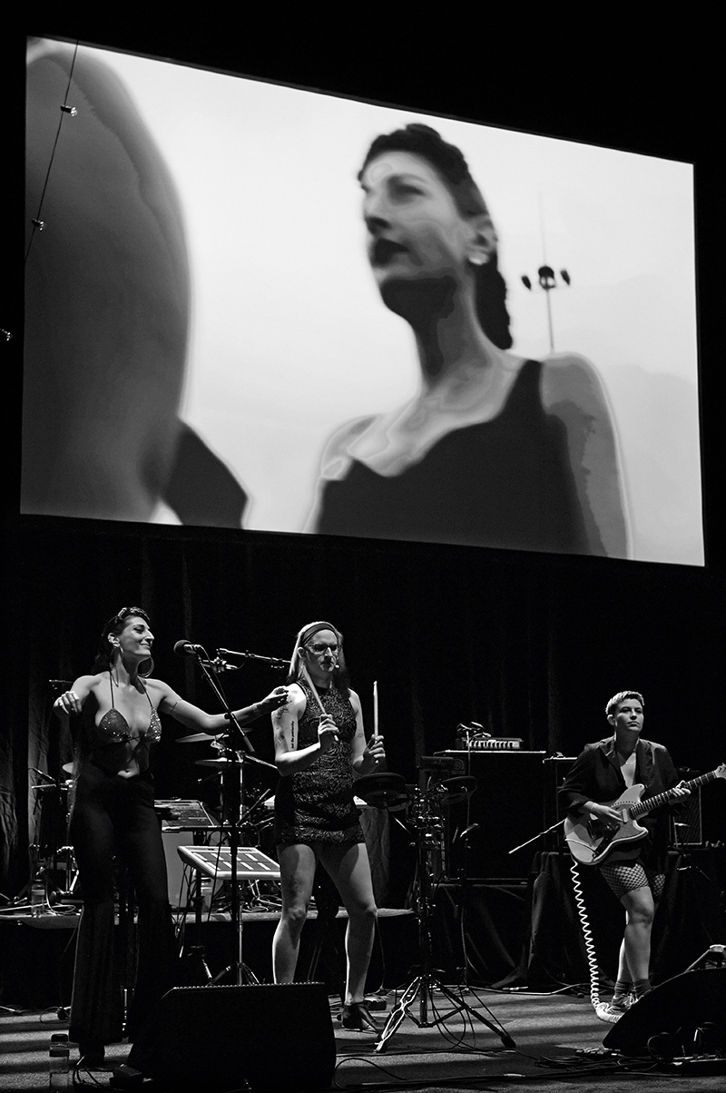 Black and white image of a trio of performers on a stage